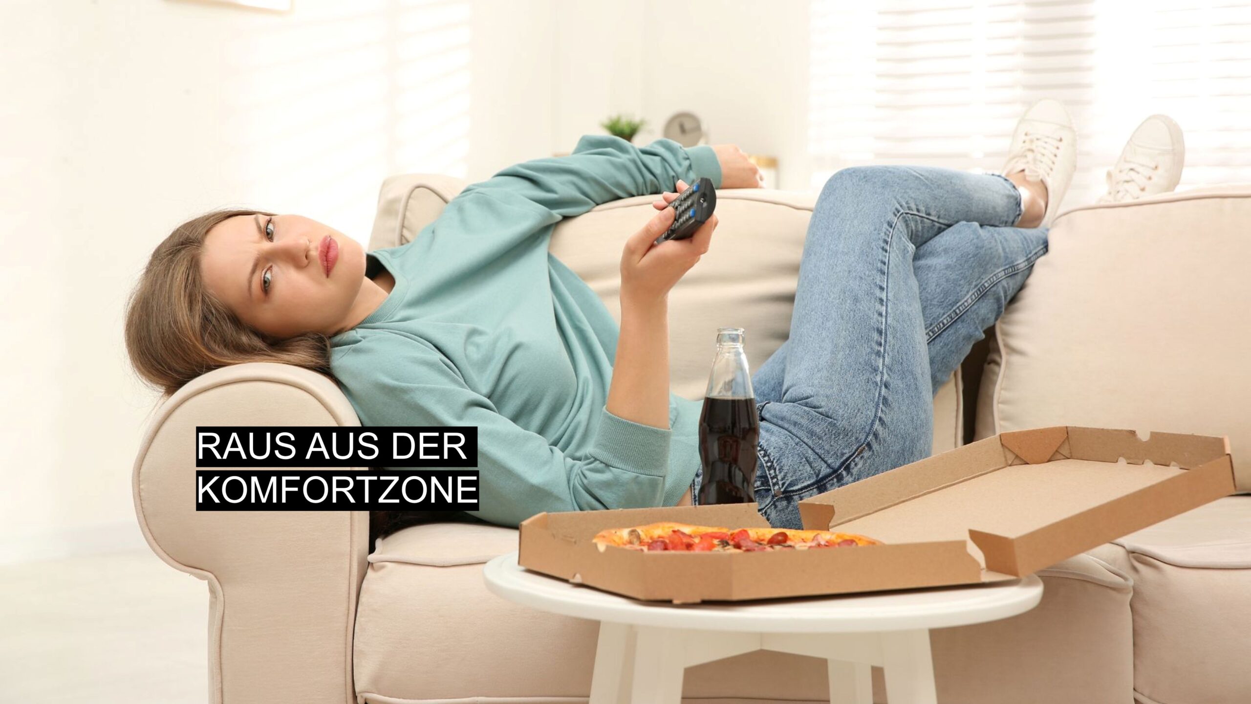 Junge Frau liegt gelangweilt auf dem Sofa mit Fernbedienung, Pizza und Cola – Komfortzone verlassen.
